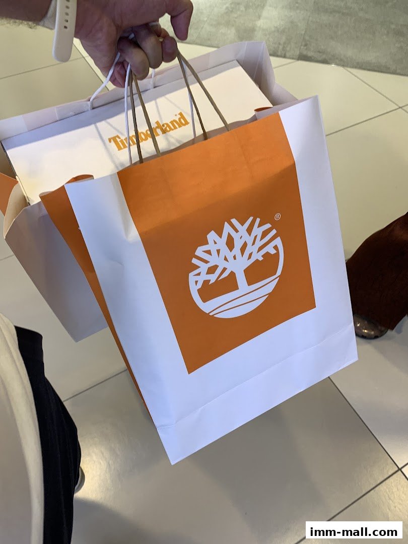 A hand holds shopping bags from Timberland, featuring the brand's logo.