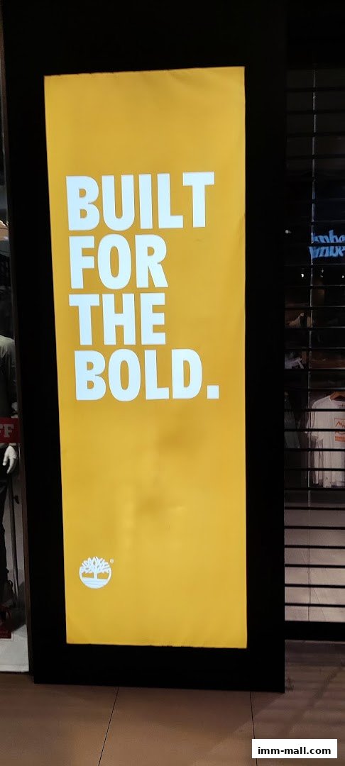 A bright yellow sign with white text saying "BUILT FOR THE BOLD." and the Timberland logo.