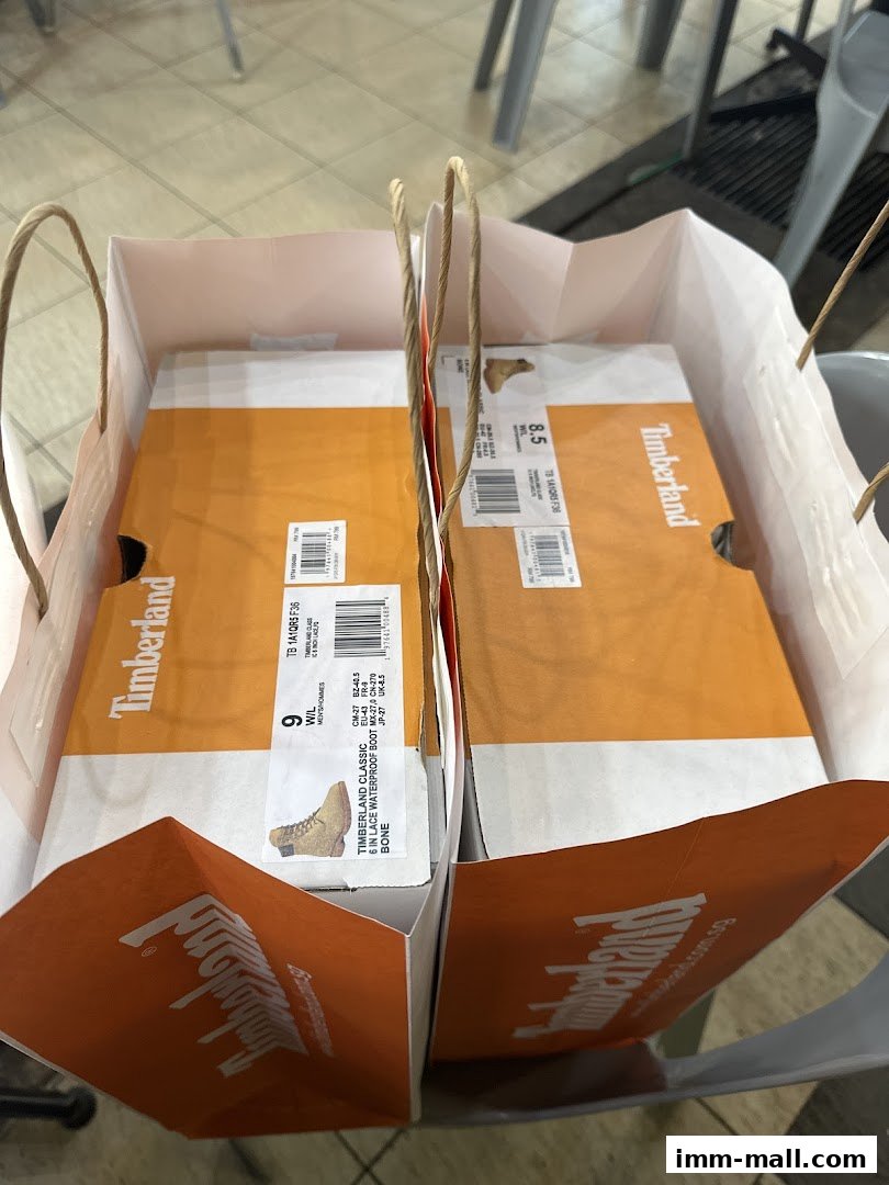 Two Timberland shopping bags filled with shoe boxes, showcasing classic boots.