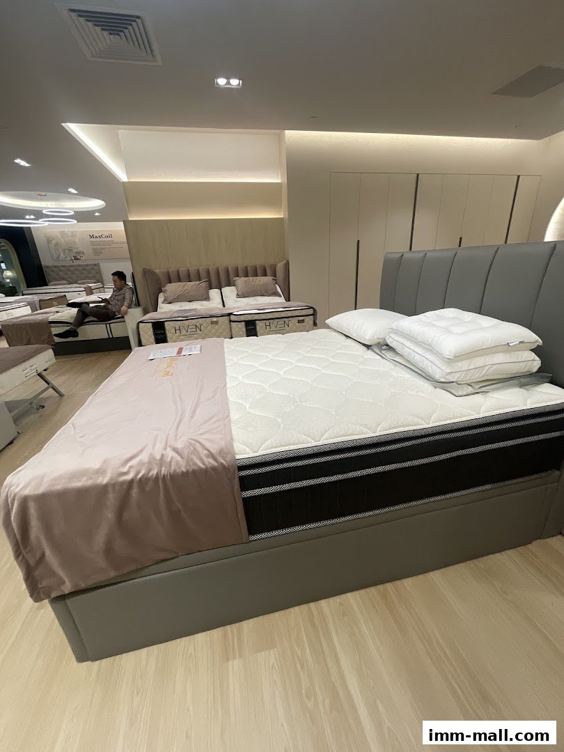 A modern mattress showroom featuring several beds with pillows and bedding.