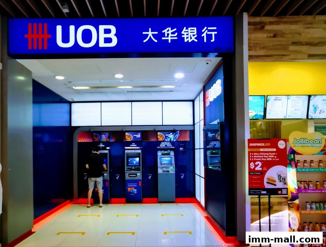 A UOB ATM area with a person using an ATM and adjacent Jollibean promotions.