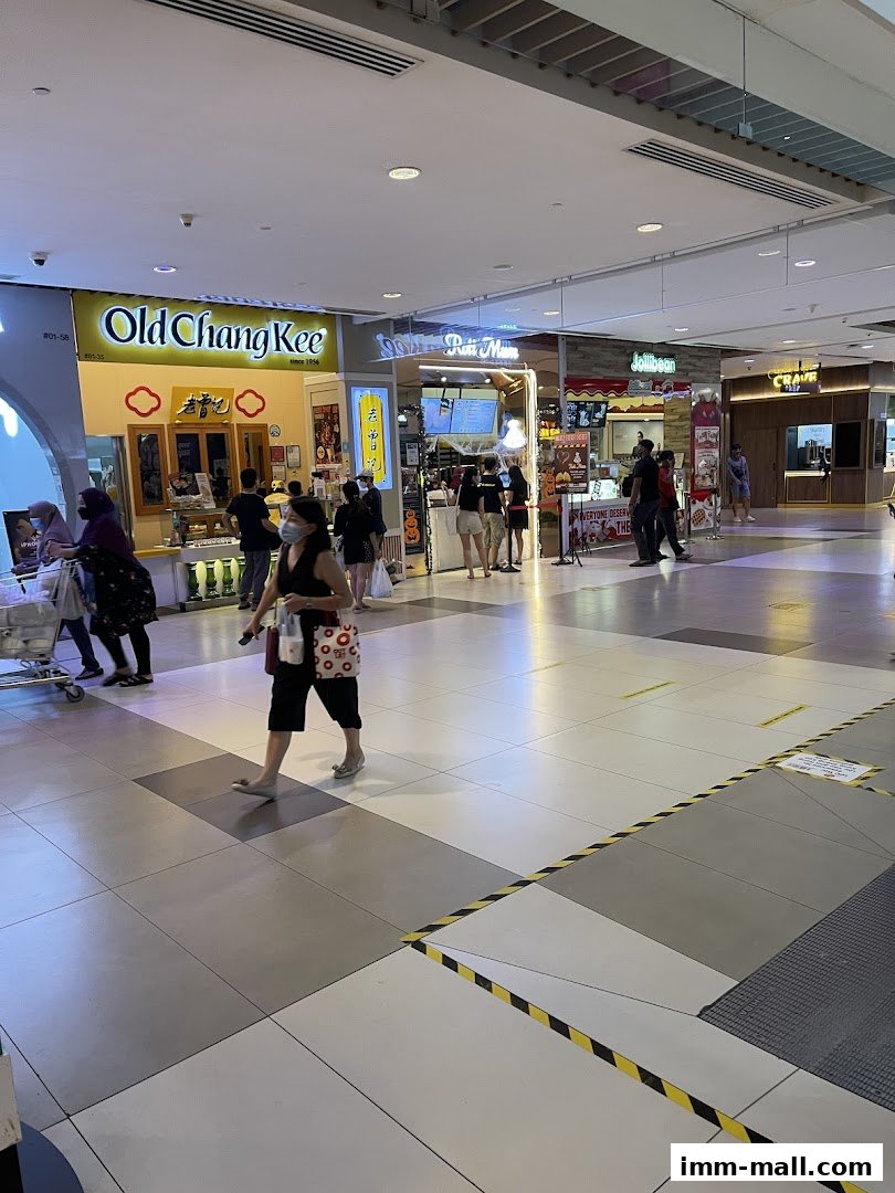 A busy mall corridor with several food stalls and shoppers walking by.
