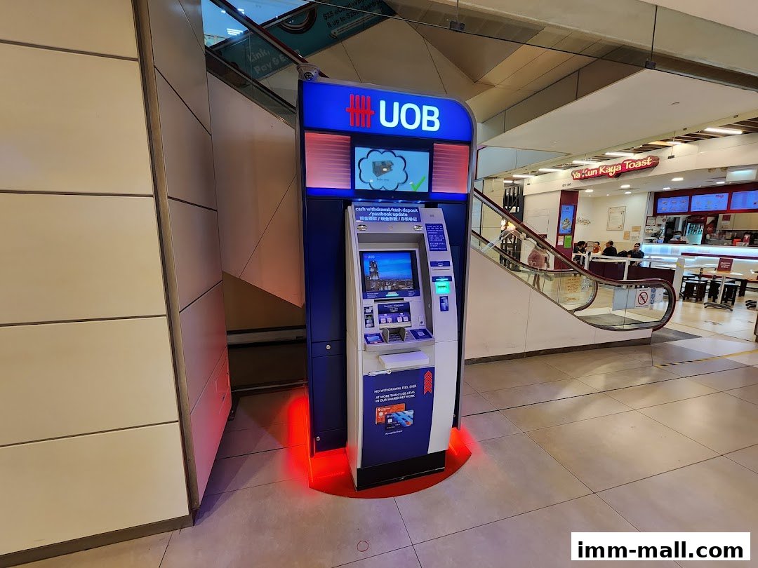 A UOB ATM machine is located next to an escalator in a shopping mall.