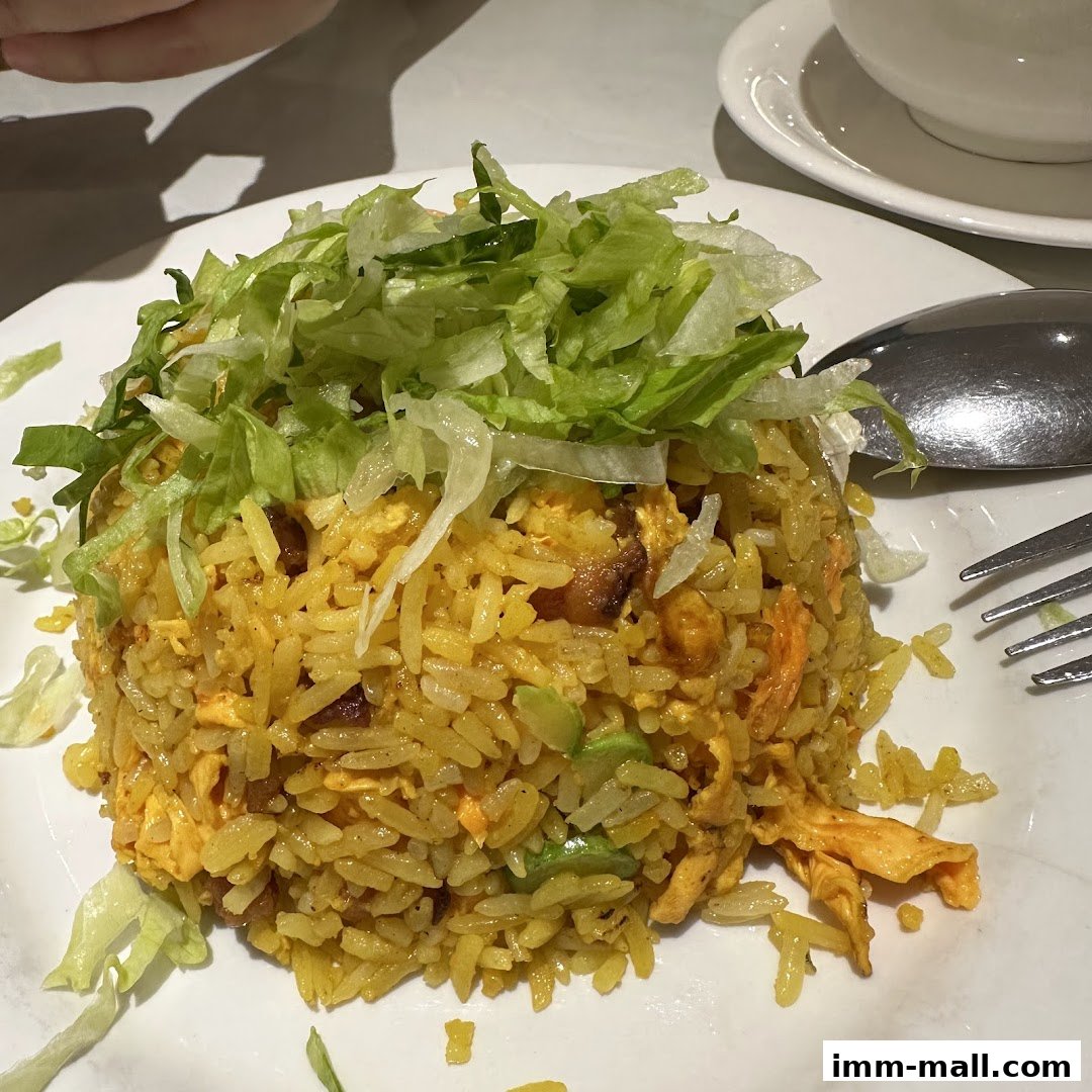 A plate of fried rice topped with shredded lettuce, served with a fork and spoon.