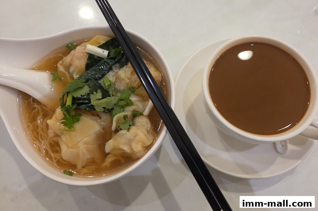 A bowl of wonton noodle soup with a cup of coffee, presented with chopsticks.