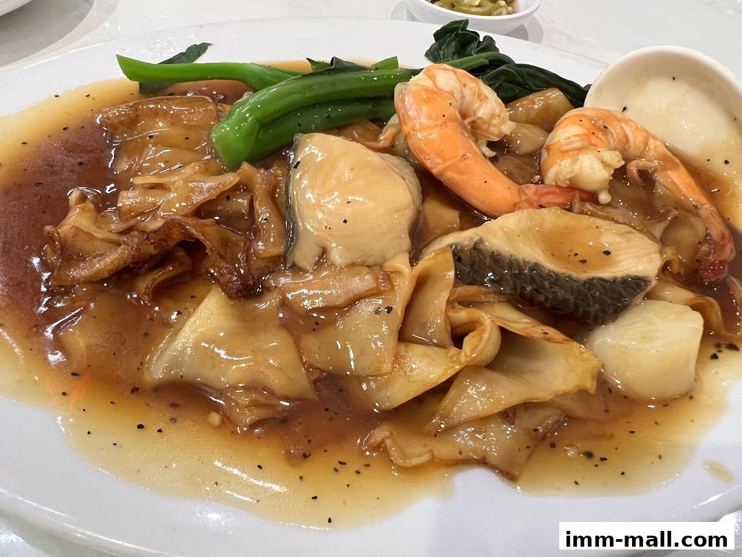 A plate of Cantonese-style noodles with seafood and vegetables in a savory sauce.