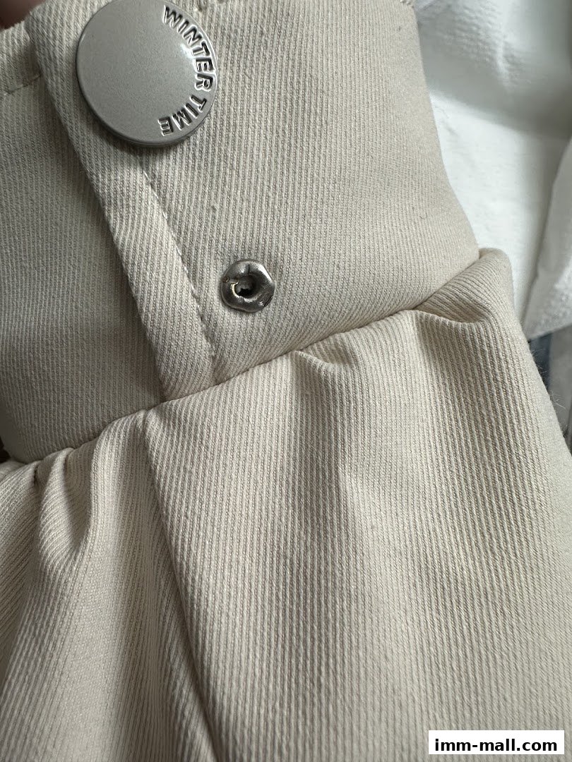 Close-up of a beige fabric garment with a branded button and snap closure.