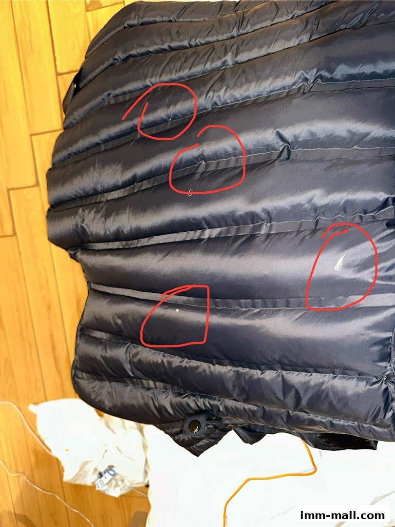 Close-up of a dark blue puffer jacket with red circles highlighting small marks.