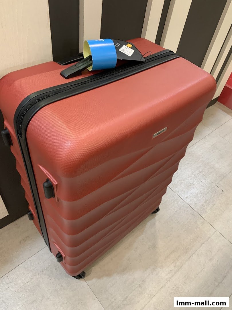 A red, textured suitcase with a blue tag and black wheels is displayed.