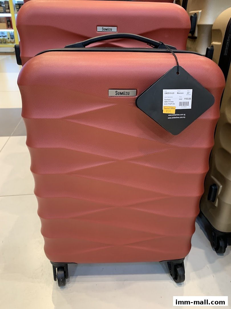 A close-up of a maroon suitcase with a price tag and branding.