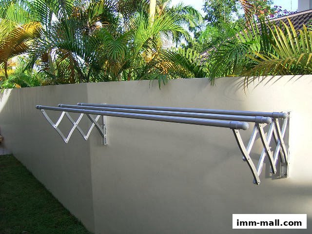 A retractable clothesline mounted on a wall with lush greenery in the background.